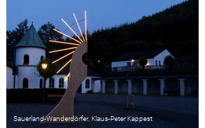 Museum von außen bei Nacht mit einer künstlerisch beleuchteten Holzfigur im Vordergrund