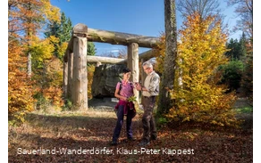Tourführung rund um den Wald-Skulpturen-Weg mit Fokus auf die Stein-Zeit-Mensch Skulptur vor blauem Himmel