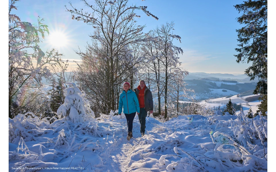 Zwei Wanderer wandern durch eine tief verschneite Winterlandschaft