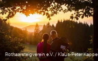 Zwei Rothaarsteig-Wanderer schauen in den Sonnenuntergang auf der Rothaarsteig-spur Sorper Panoramapfad